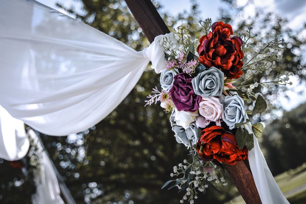 Outdoor wedding ceremony setup with white draped fabric and floral arrangements.
