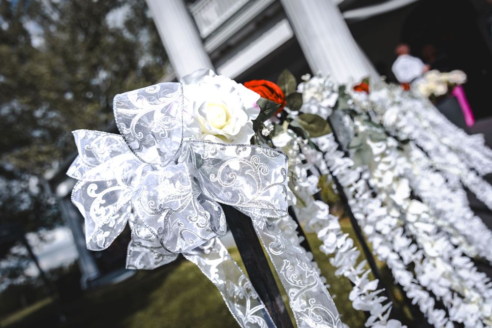 White decorative bows and ribbons adorning wedding ceremony decor against a dark background.