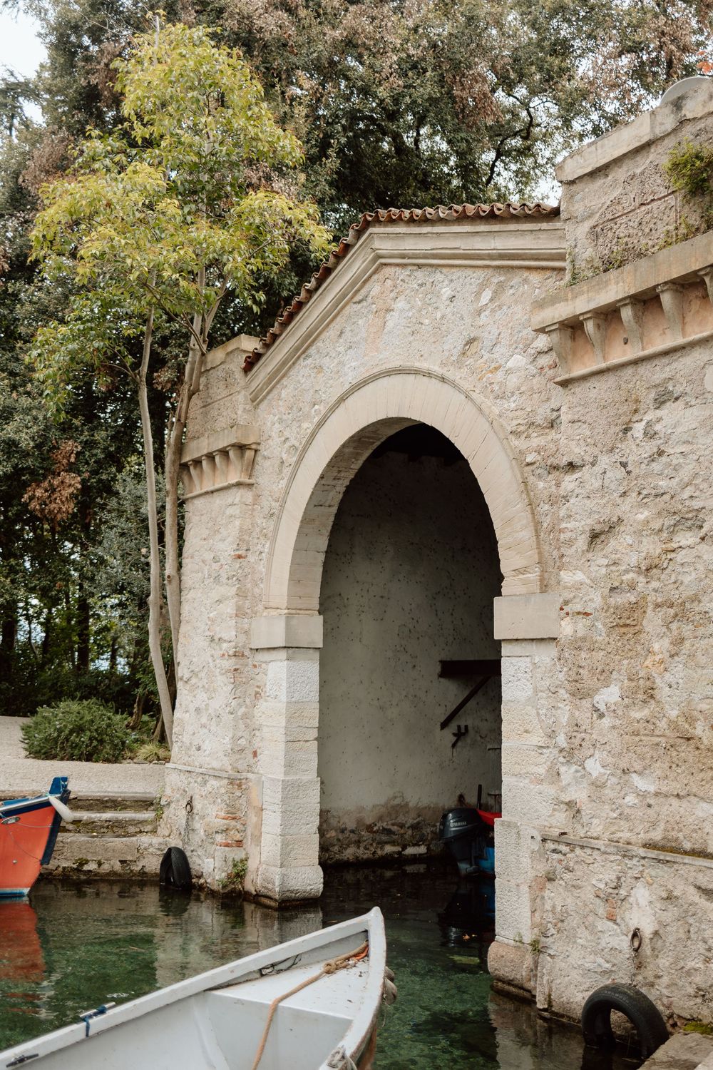 Stone archway entrance to a canal waterway with boats visible through multiple connected arched openings.