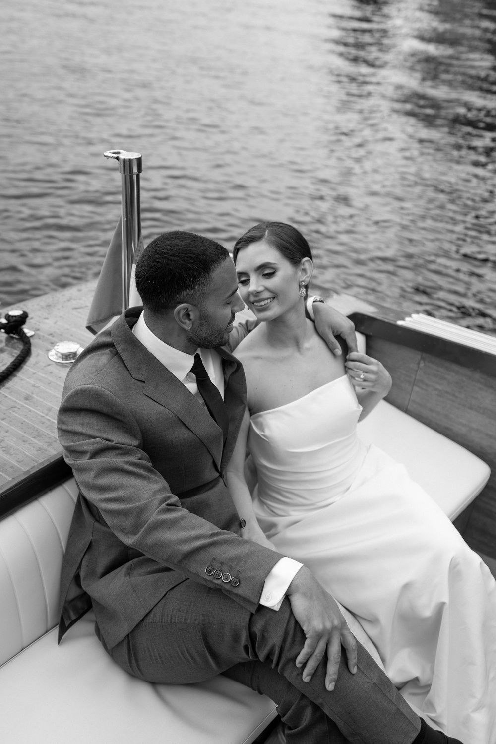 Black and white romantic candid photos of newlyweds sharing laughter and intimate moments on a boat.
