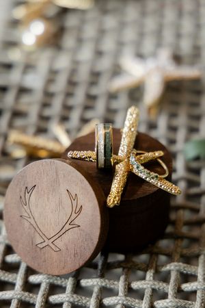 Close up of wooden cufflinks with antler logo and sparkly gold cross design on textured background.