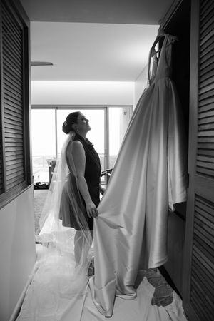 Series of wedding dress silhouettes hanging in bridal preparation room with natural window light.