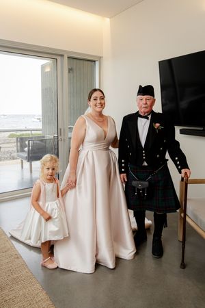 Wedding party in formal attire featuring traditional Scottish kilt and elegant cream-colored gowns.