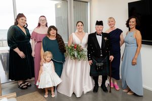 A row of people in formal attire stand together in a line at a wedding celebration.