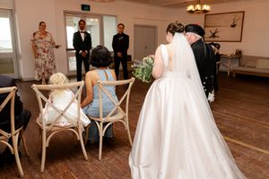Wedding party members socializing in an elegant venue with natural lighting and floral arrangements.