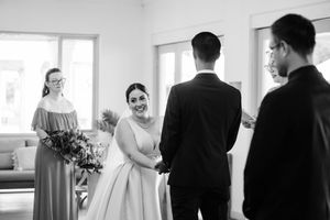A black and white wedding ceremony moment showing couple exchanging vows with bridesmaids in attendance.