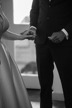Black and white photo of a bride and groom exchanging rings during their wedding ceremony.