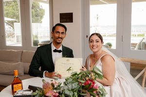 A bride and groom sitting at a table with colorful floral arrangements and refreshments during their wedding reception.