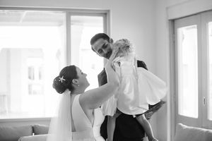 Black and white photo capturing an intimate wedding moment in a bright, window-lit room.