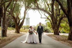 Tree-lined pathway creates natural archway for elegant wedding portraits.