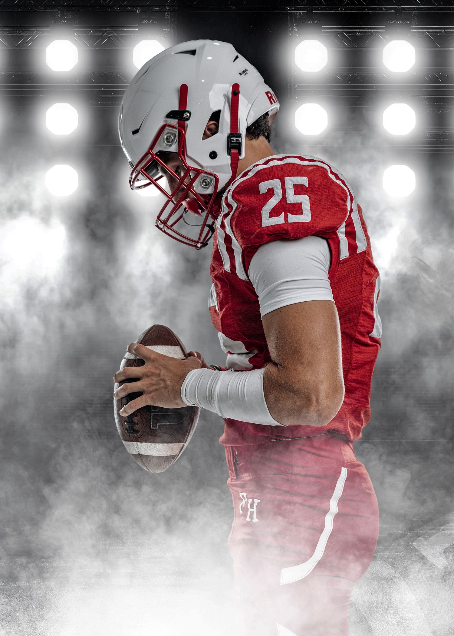 Football player in red and white uniform stands in atmospheric stadium lighting.