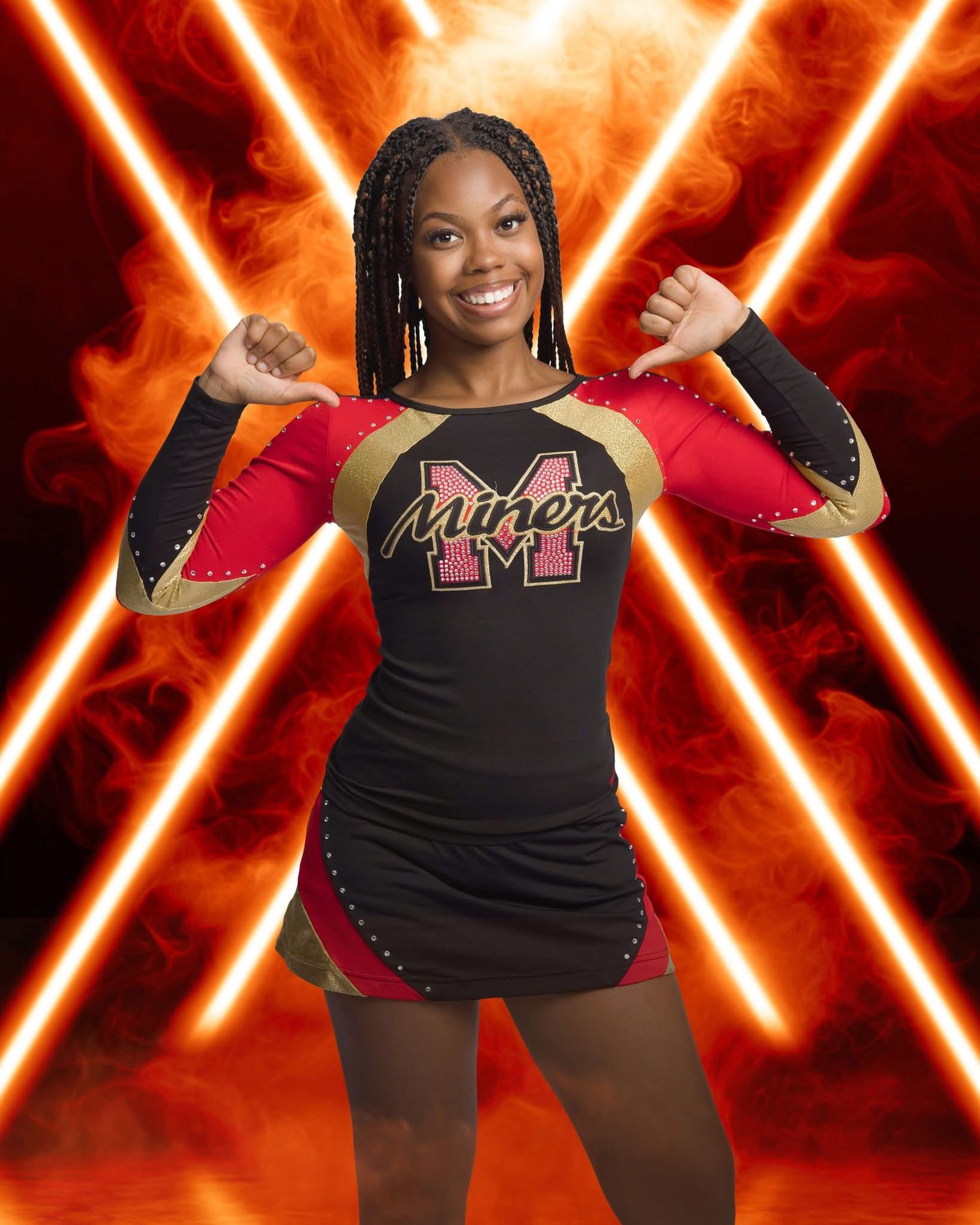 Cheerleader in black uniform with red accents performs against dramatic orange lighting background.