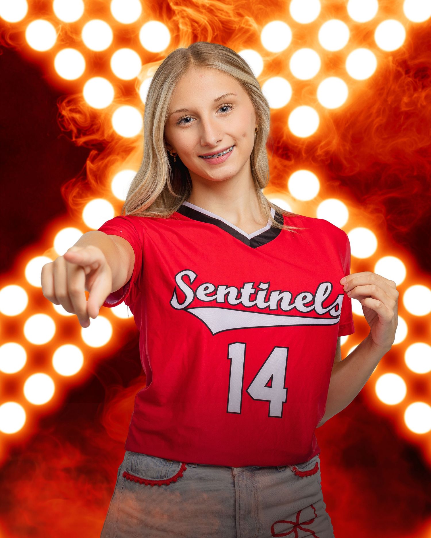 Student athlete in red Sentinels volleyball uniform poses against bright spotlights.