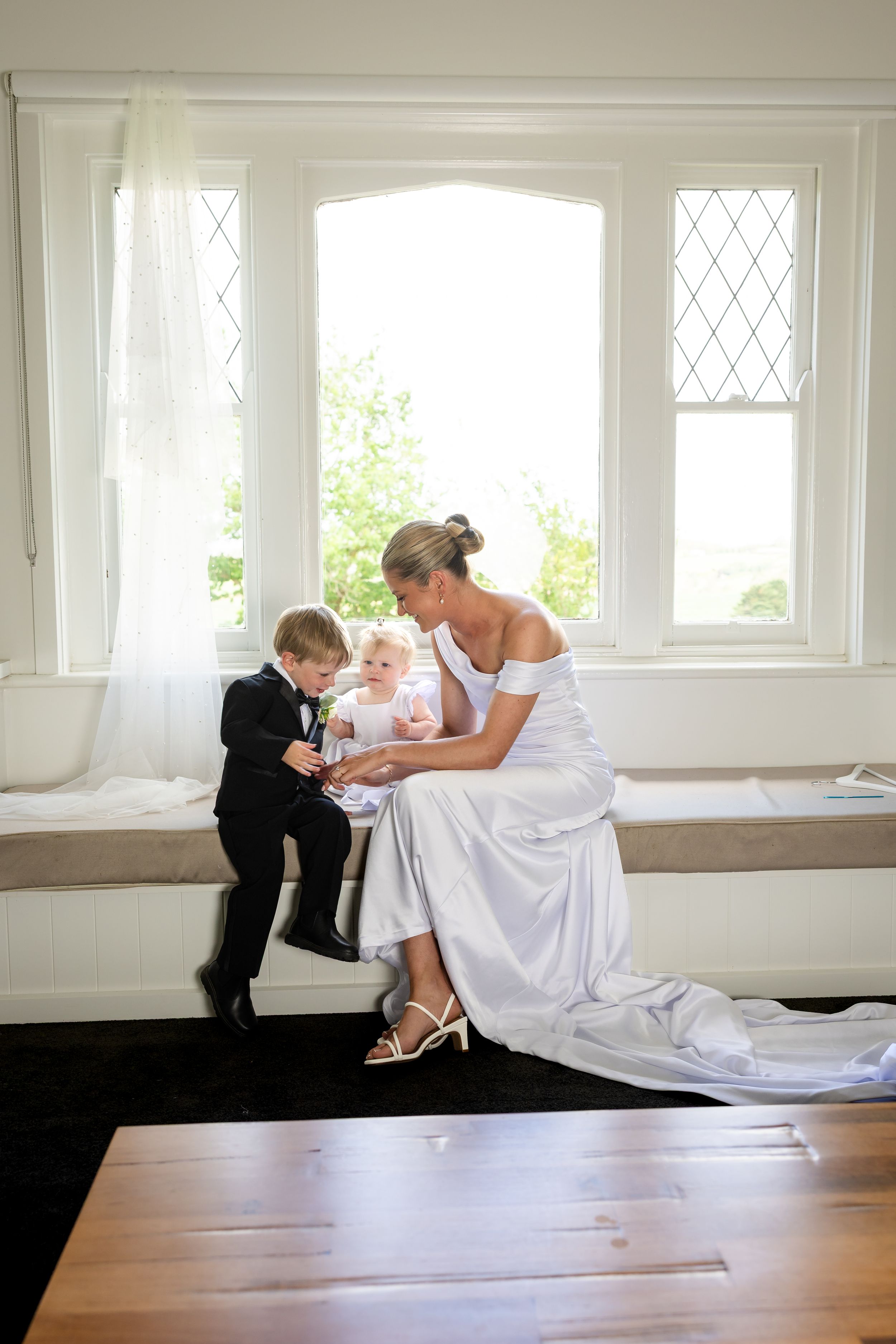 A series of artistic wedding photos showing a couple in black and white formal attire interacting on a hardwood floor.