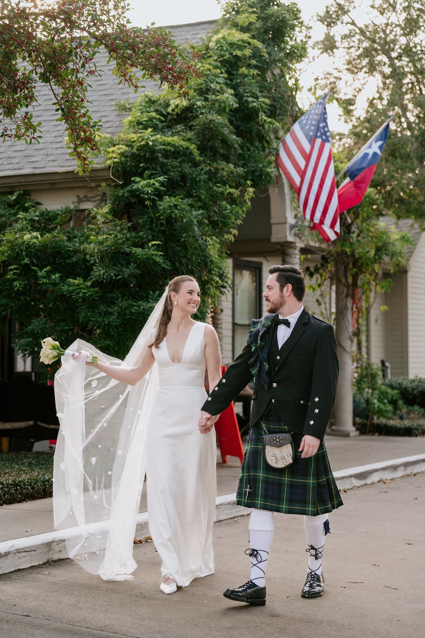 A bride and groom walking together out front of Ouisie's Table in Houston, Tx.