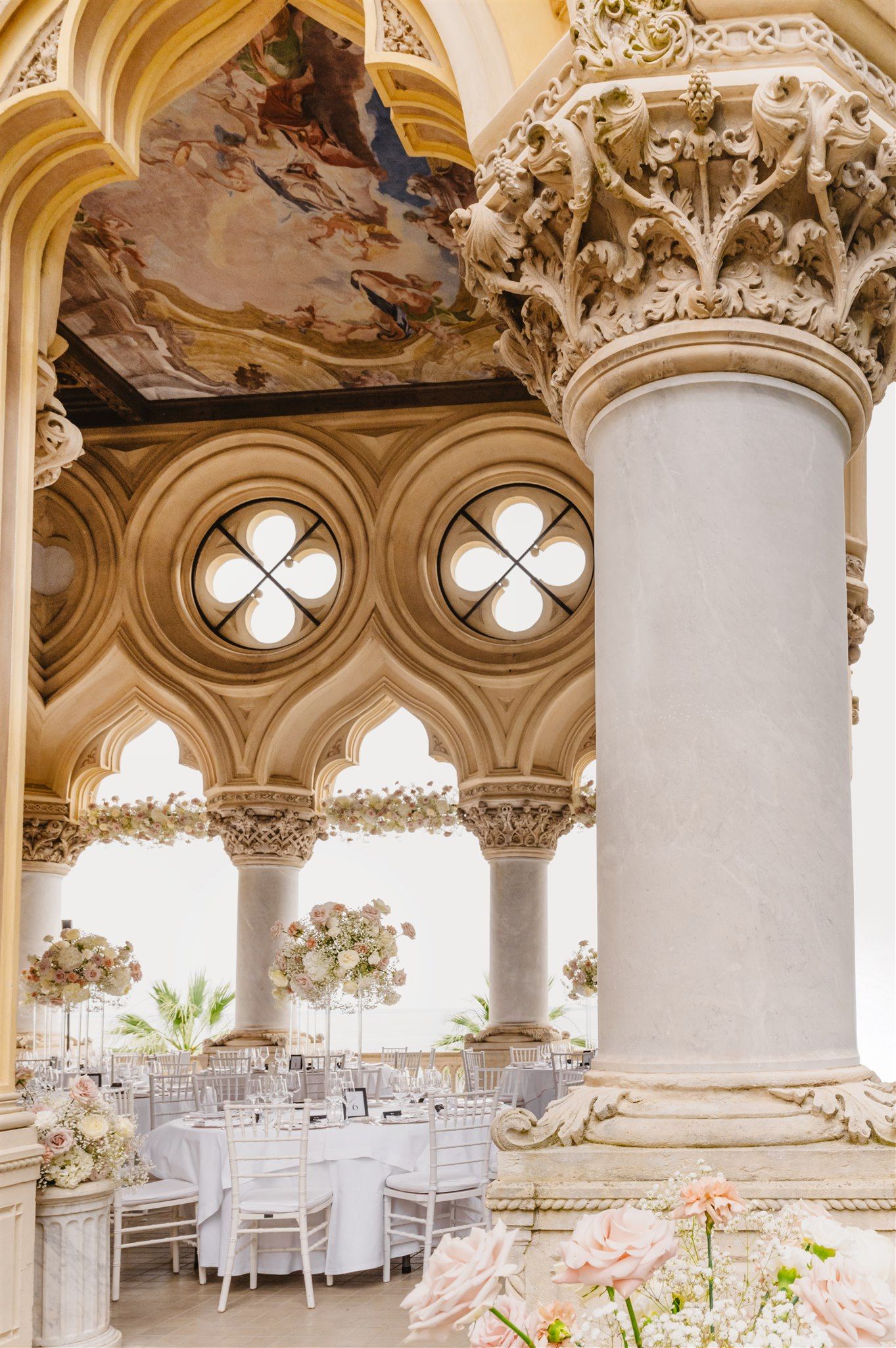 Luxurious wedding venue with ornate baroque ceiling details and white table settings.