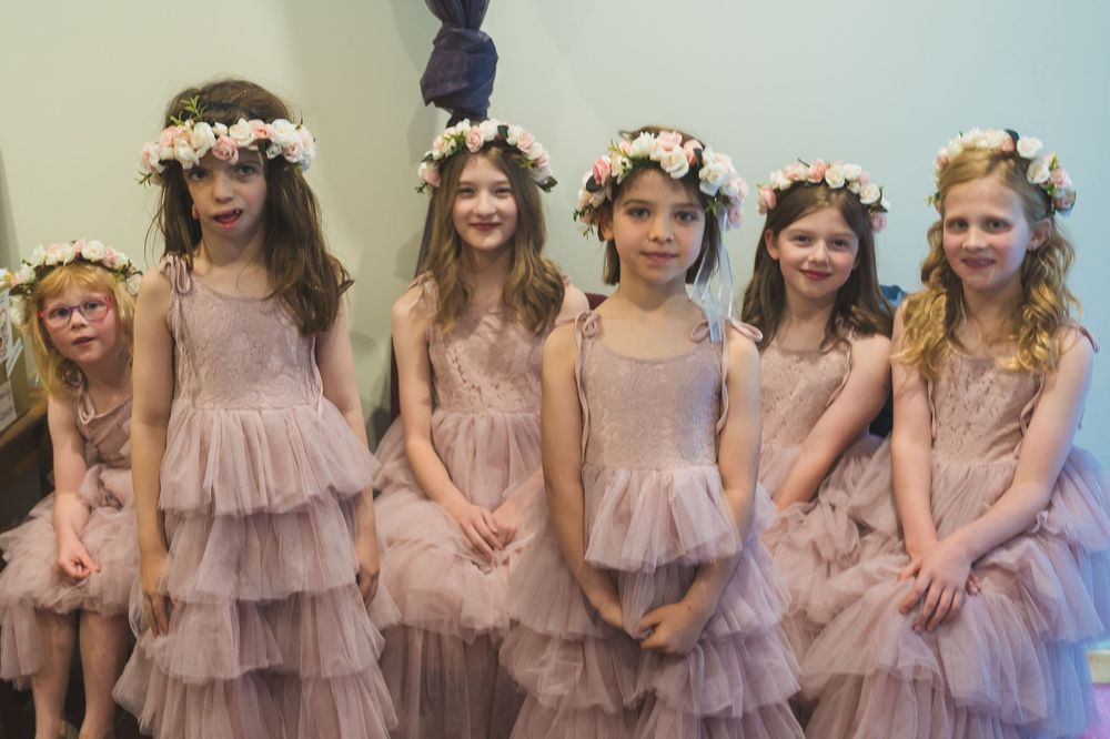 A group of bridesmaids wearing flowy lavender dresses and floral crowns pose together in a dreamy wedding photo sequence.