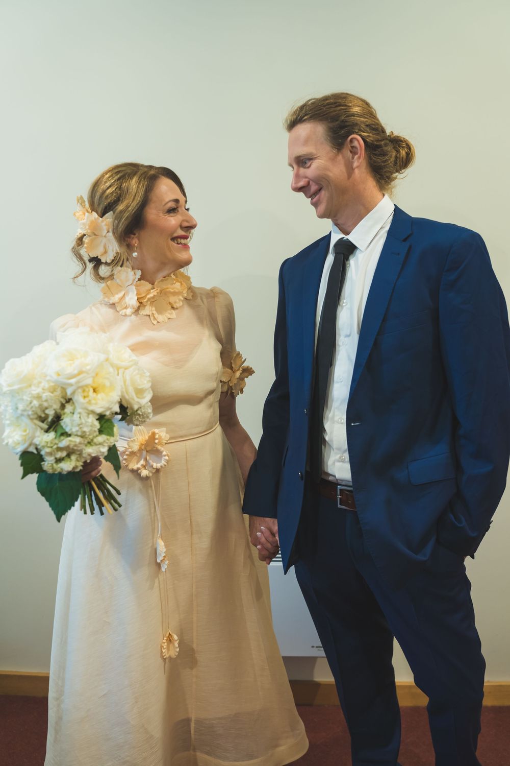 A happy couple sharing a joyful moment at their wedding, with the bride holding a beautiful bouquet of flowers.