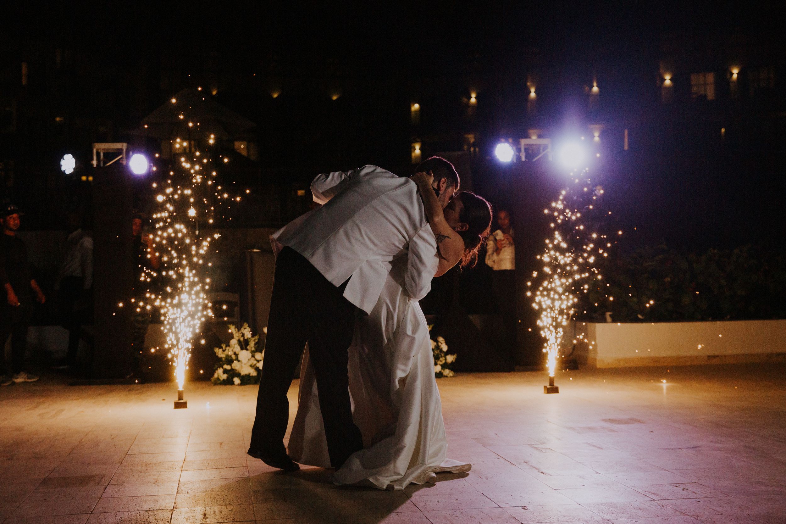 Wedding couple dips during first dance with sparklers creating dramatic lighting effect.
