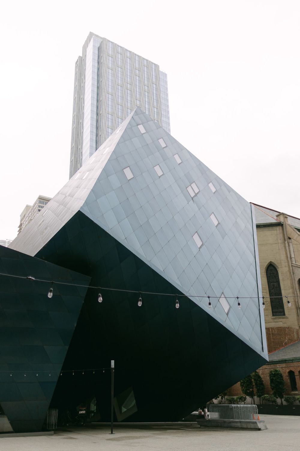 Contemporary angular architectural building with geometric white panels and windows against an overcast sky.
