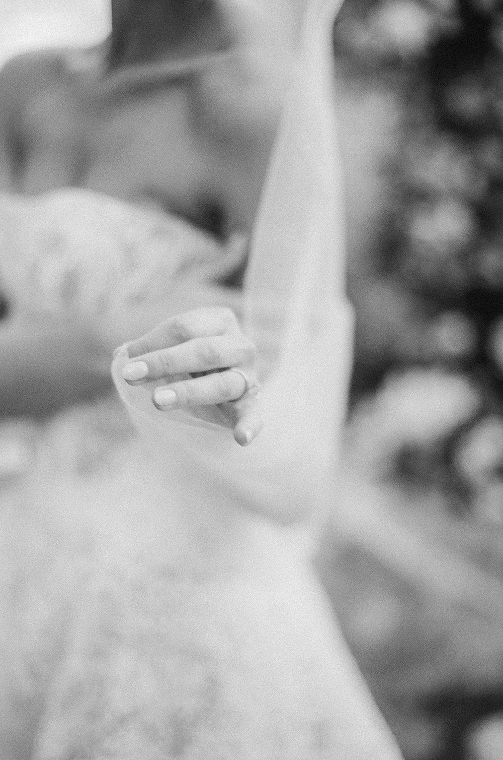 A close-up black and white photograph of a delicate finger pointing upward against a soft, blurred background.