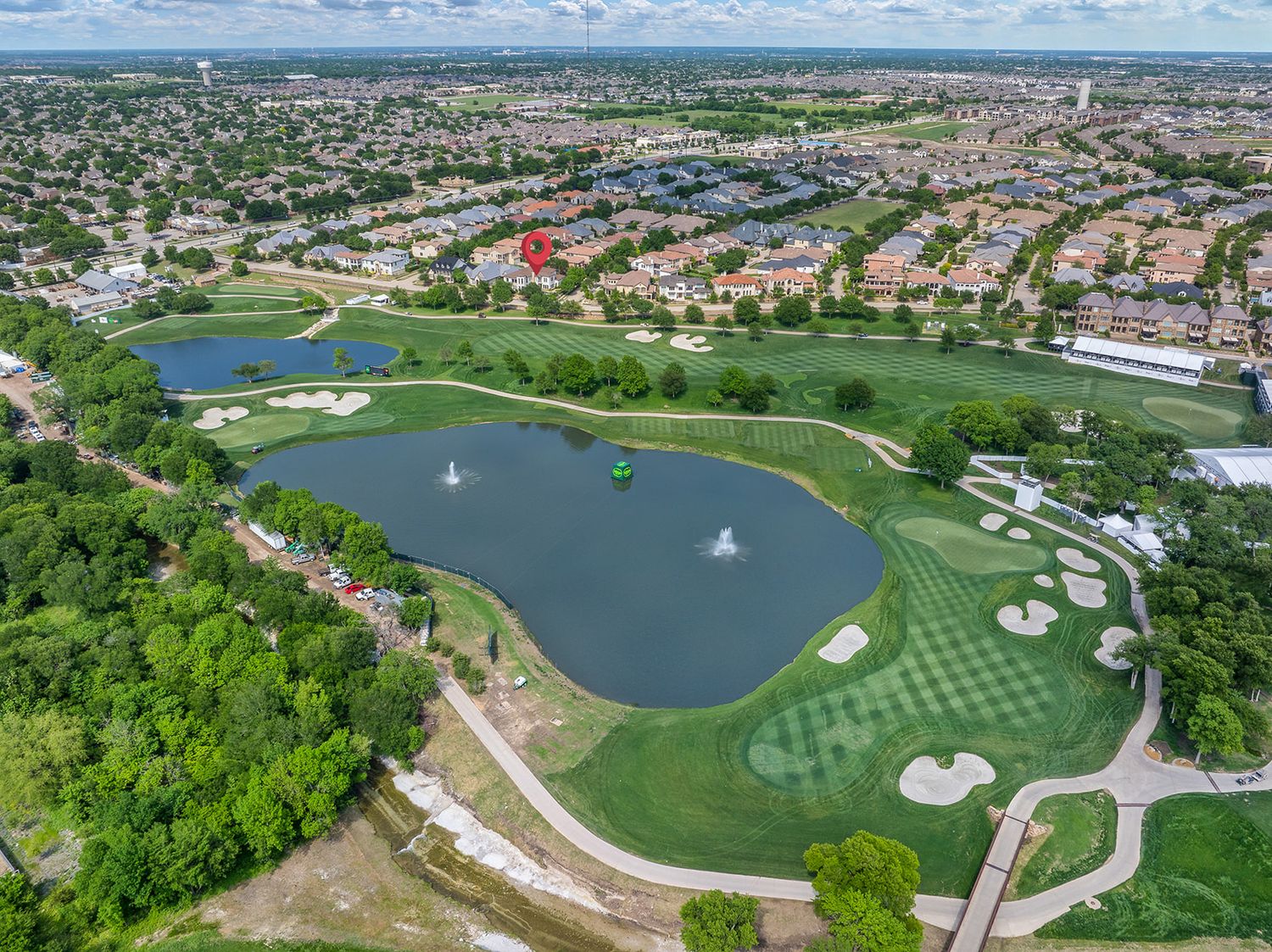 Panoramic aerial view of a golf course with multiple lakes, greens, and surrounding residential development on a sunny day.