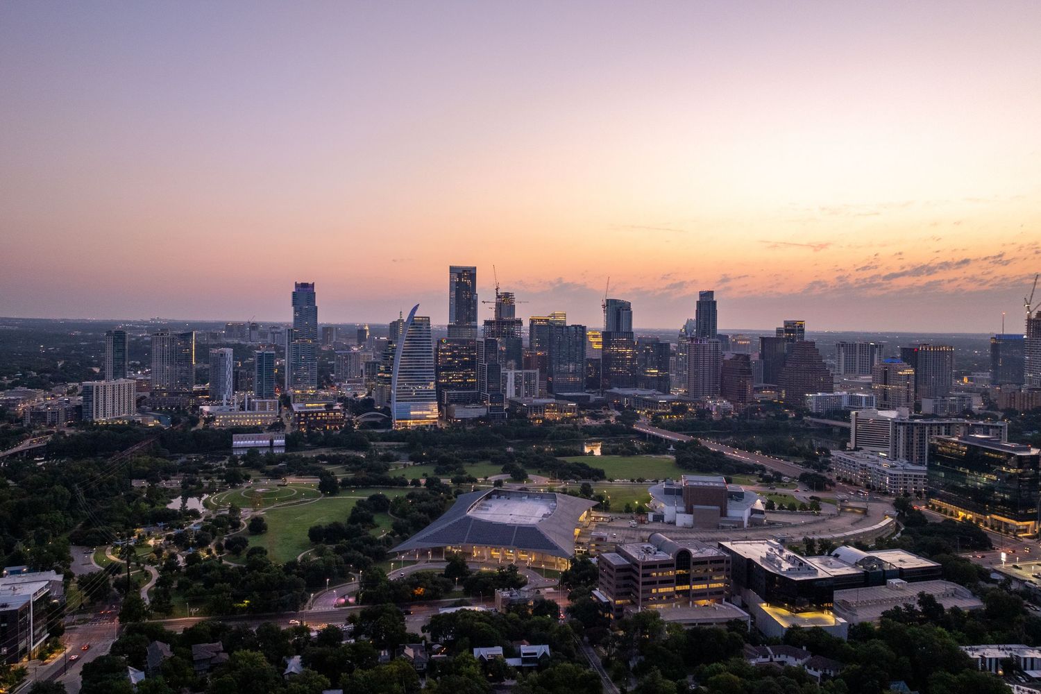 Panoramic aerial view of downtown Atlanta's skyline with skyscrapers silhouetted against a colorful sunset sky.