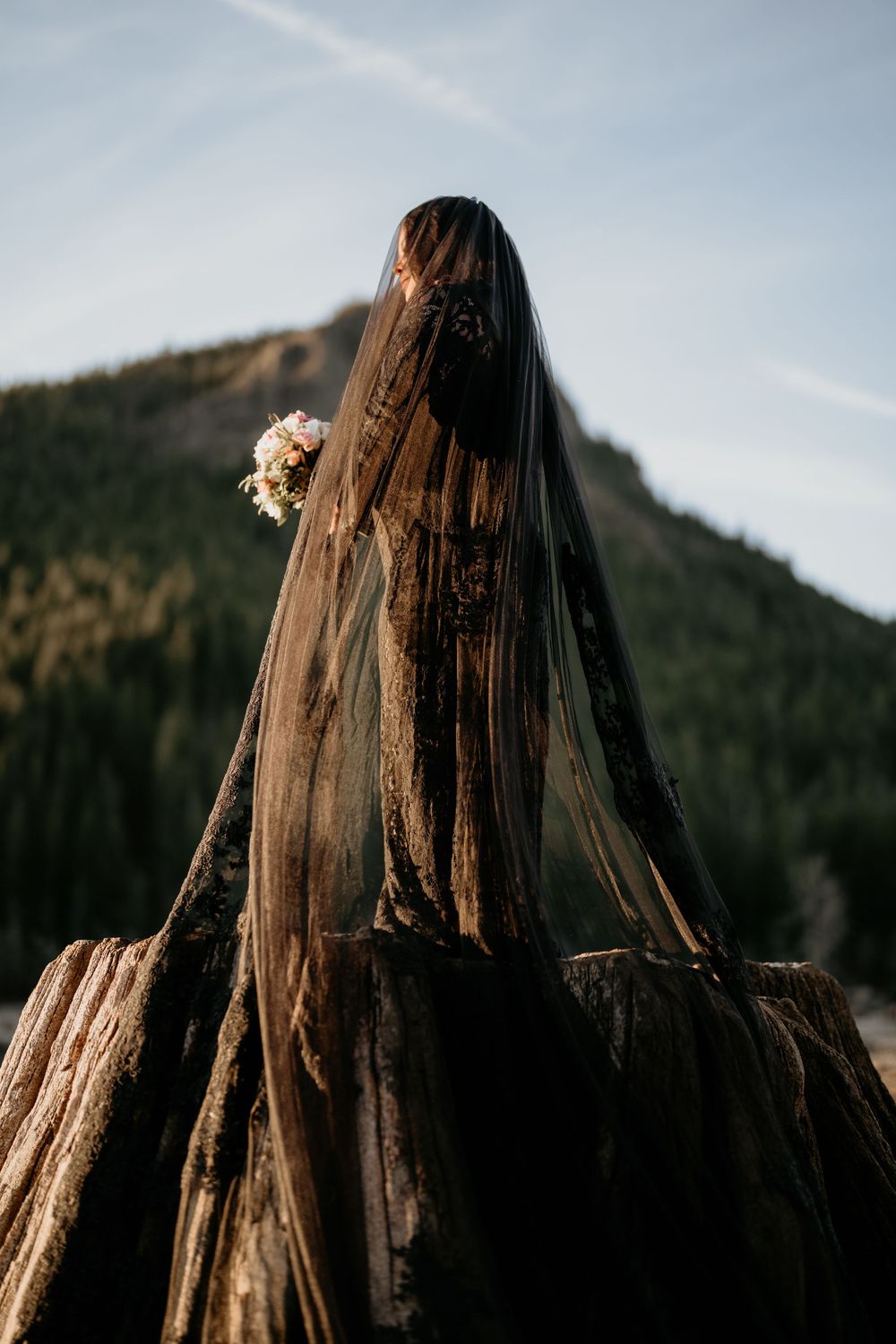 Bride in black dress looking out into the mountains at Rattlesnake Lake.