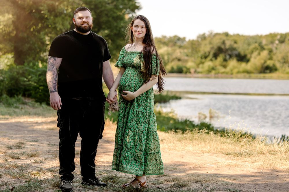 A romantic outdoor photoshoot at sunset with a couple standing together near a serene lake in fort worth