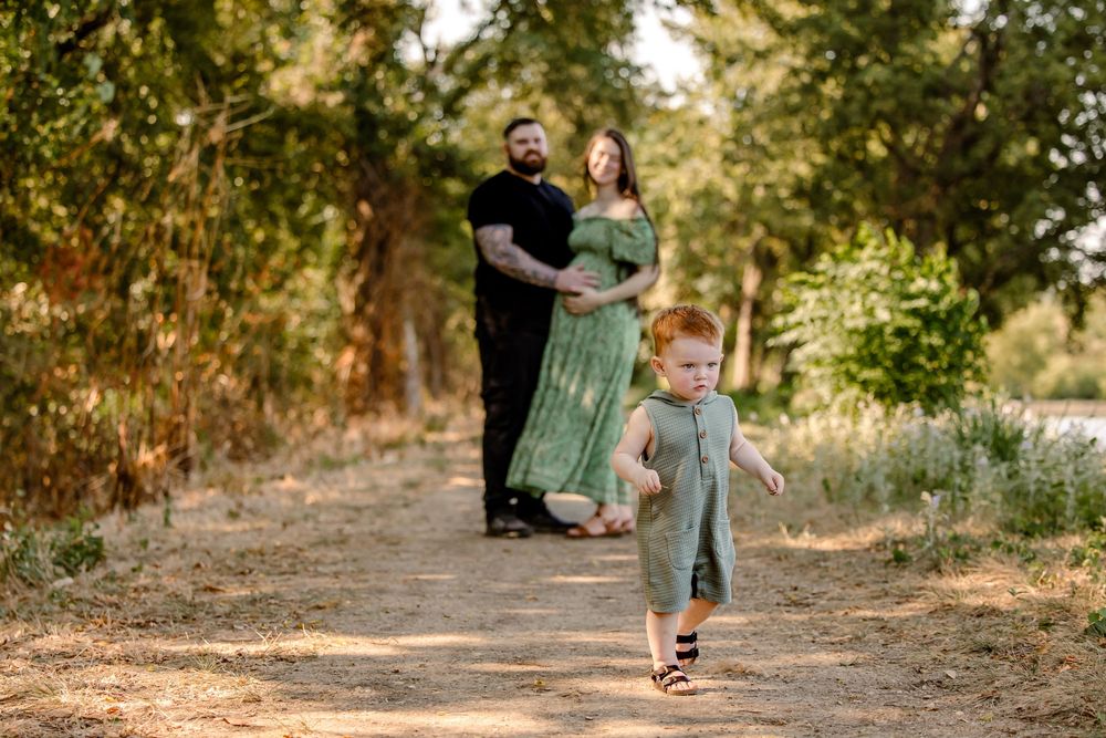 Family walking along a sunlit wooded path during golden hour photography session.