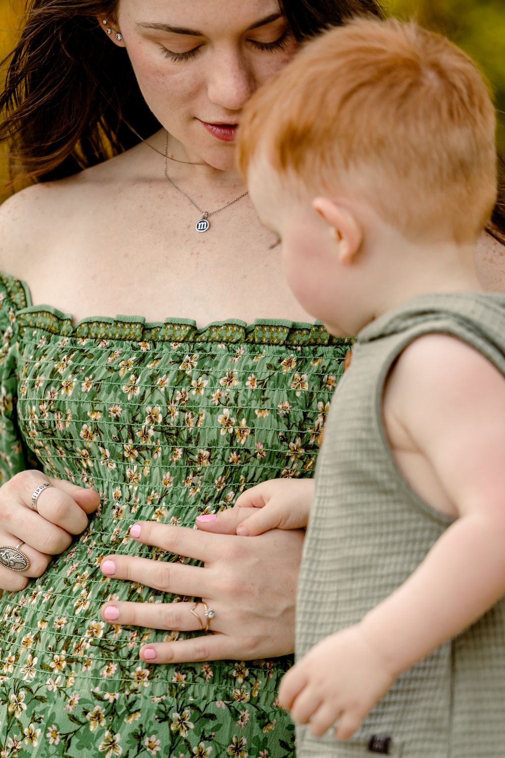 Close-up sequence showing a baby in green exploring and touching a floral printed dress or fabric.