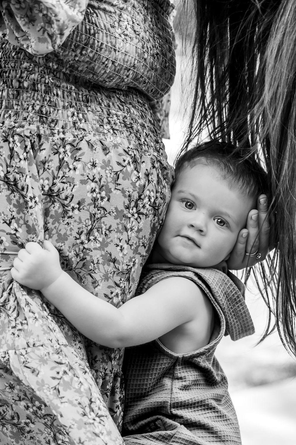 A baby in sleeveless outfit rests against moms baby bump in fort worth maternity photo session