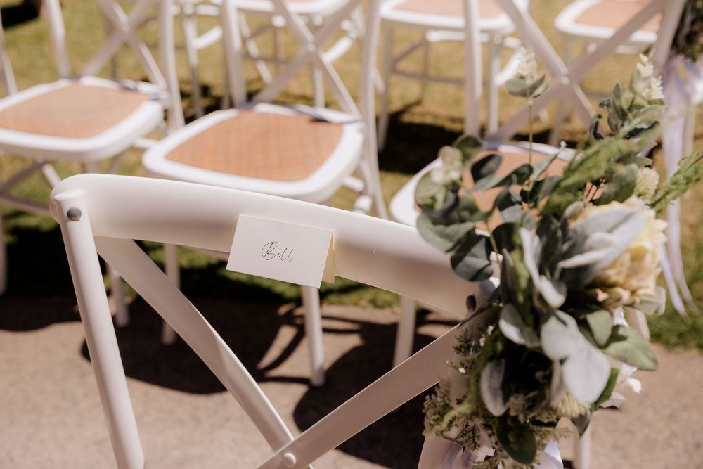 White folding chairs with floral arrangements set up for an elegant wedding ceremony.