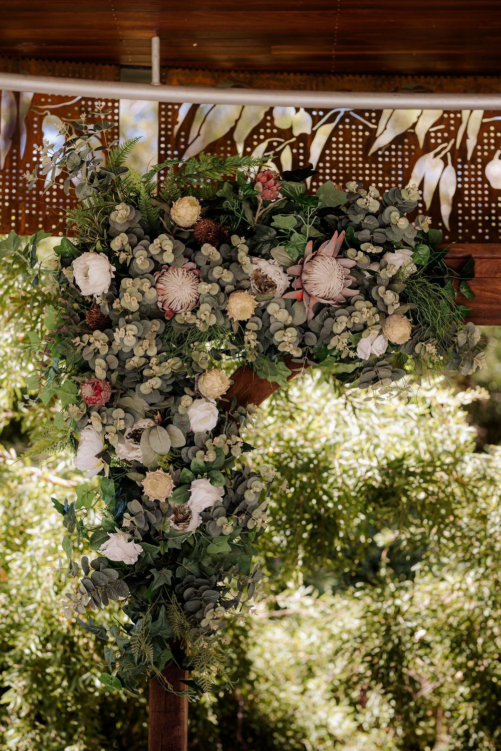 Luxurious floral arch with pink and white roses adorned with greenery creates an elegant garden wedding setting.