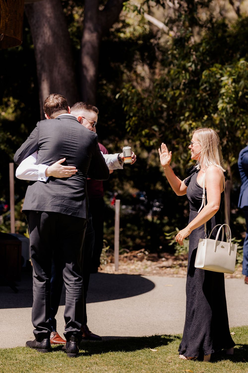 Candid outdoor scene showing people greeting each other on a sunny day in a park setting.