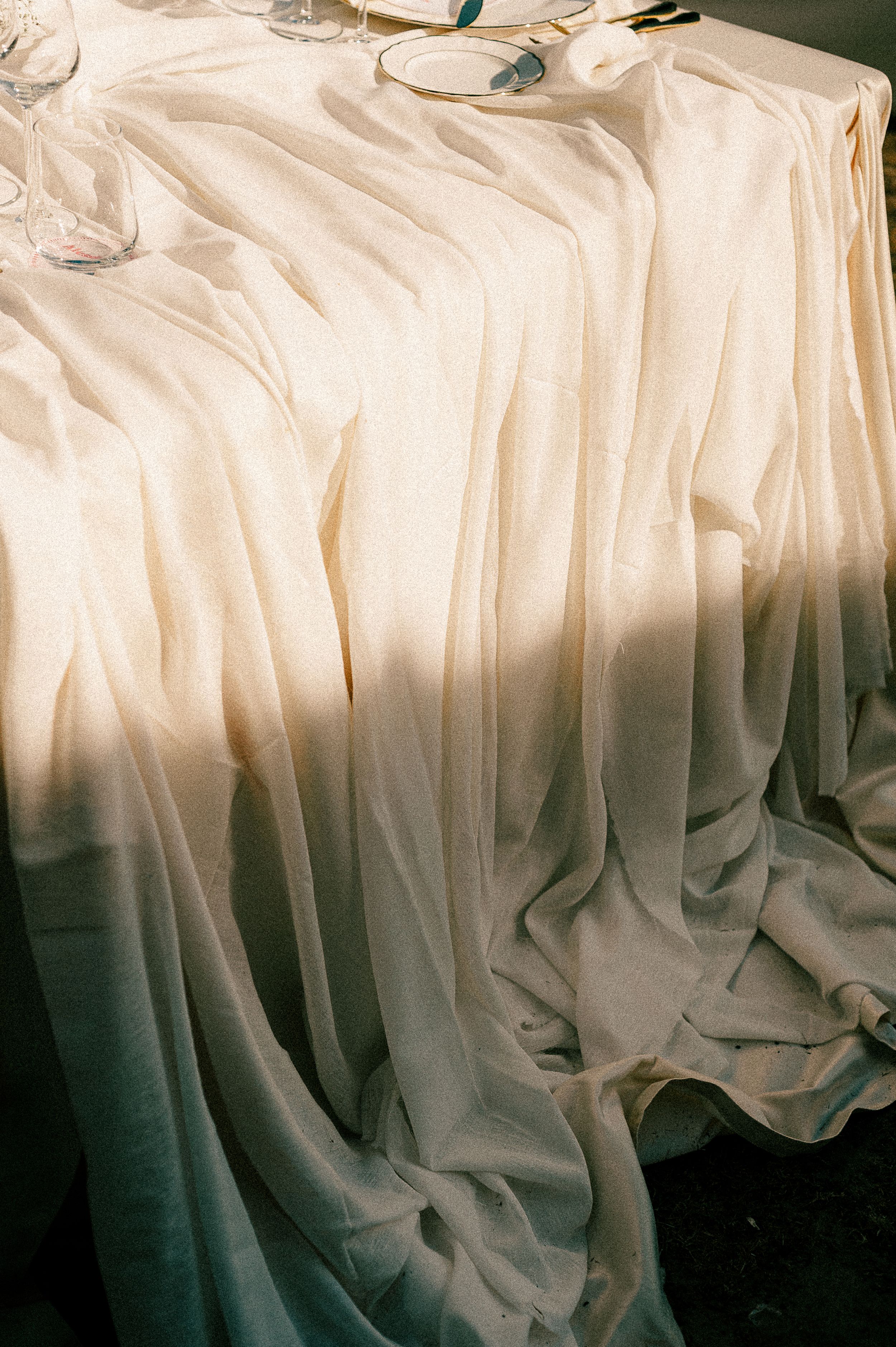 Elegant white fabric draping with soft folds and shadows creating a romantic texture.