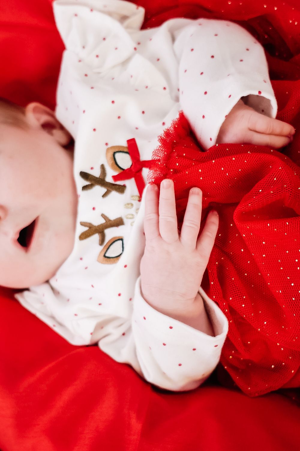 A series of close-up photos showing a sleeping baby in white clothing against a bright red background.