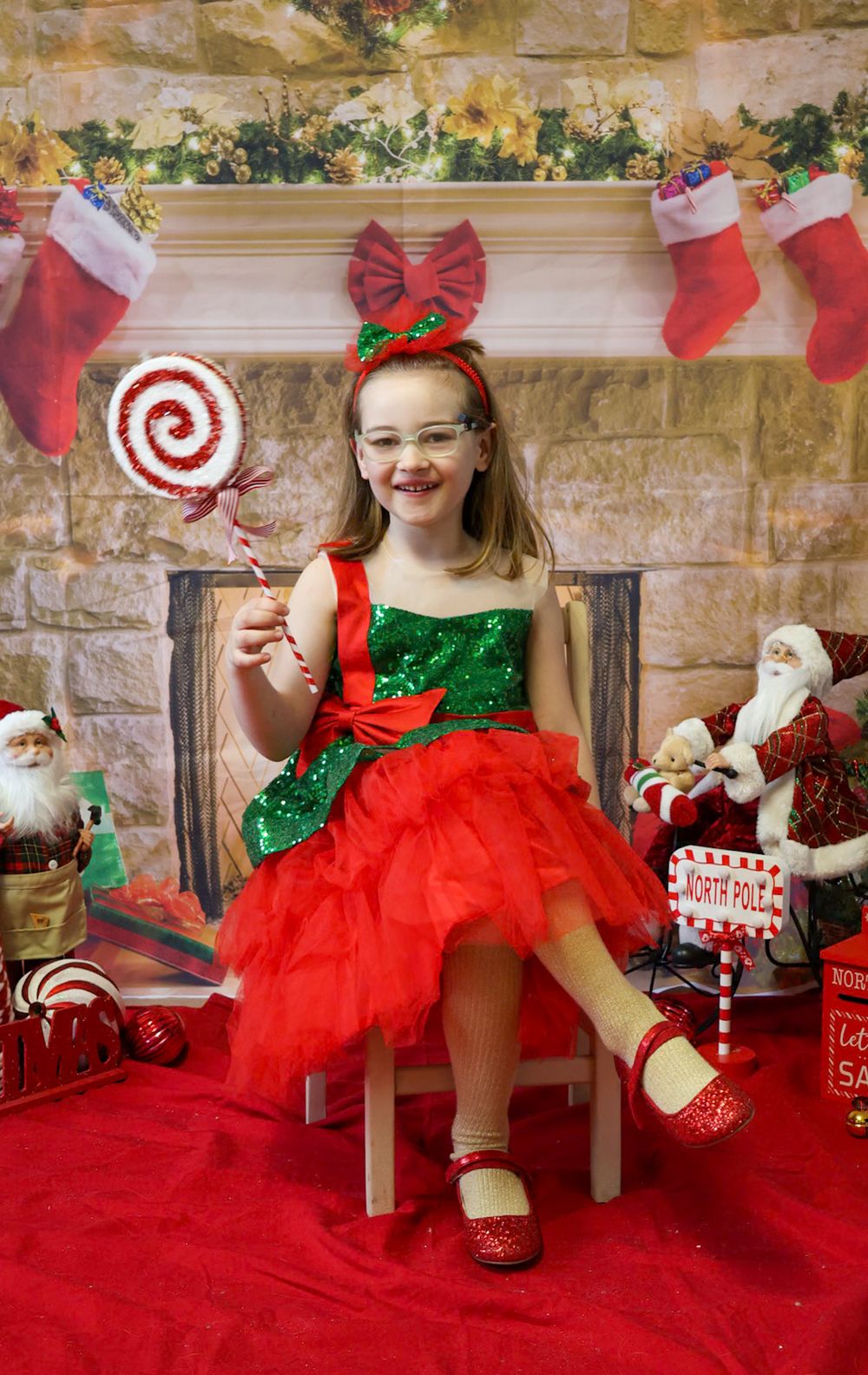 A festive holiday photo series featuring red tulle dresses, sparkly shoes, and Christmas decorations against a stone wall.