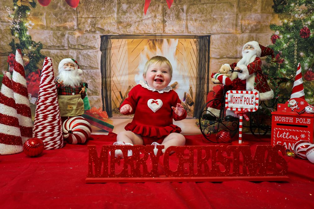 Festive Christmas scene with red velvet dress, candy canes, and holiday decorations against stone wall backdrop.