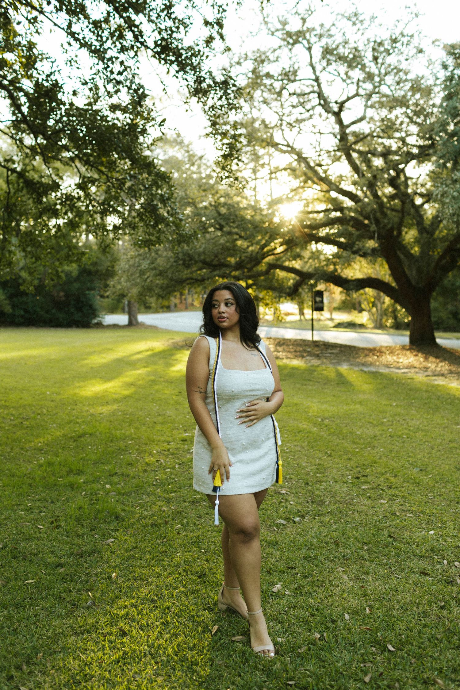 A Georgia Southern University graduate stands in a field topped with Spanish moss on campus