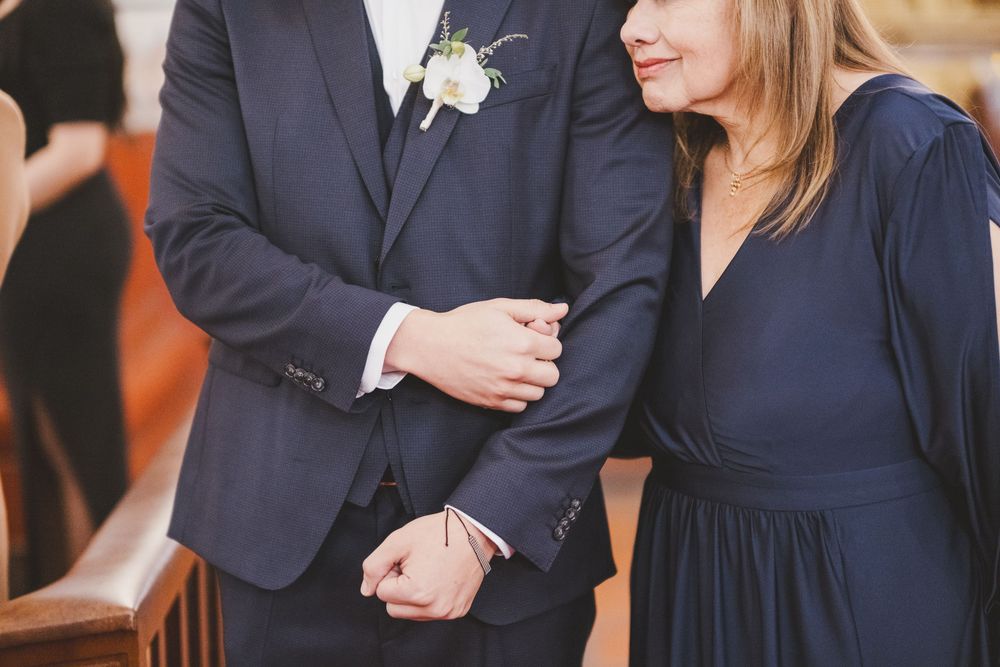 Wedding attendees wearing coordinated navy blue formal attire with boutonniere detail at formal event.