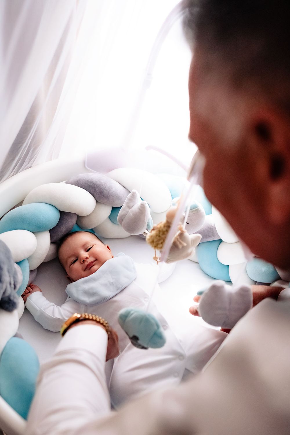 Newborn baby lying on white bedding with blue and gray cloud-shaped pillows.