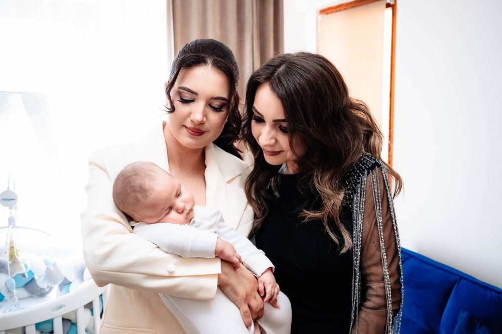 Two women in a nursery sharing a tender moment with a newborn baby.