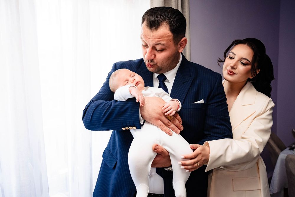 Couple sharing an intimate moment with their newborn baby near a window.