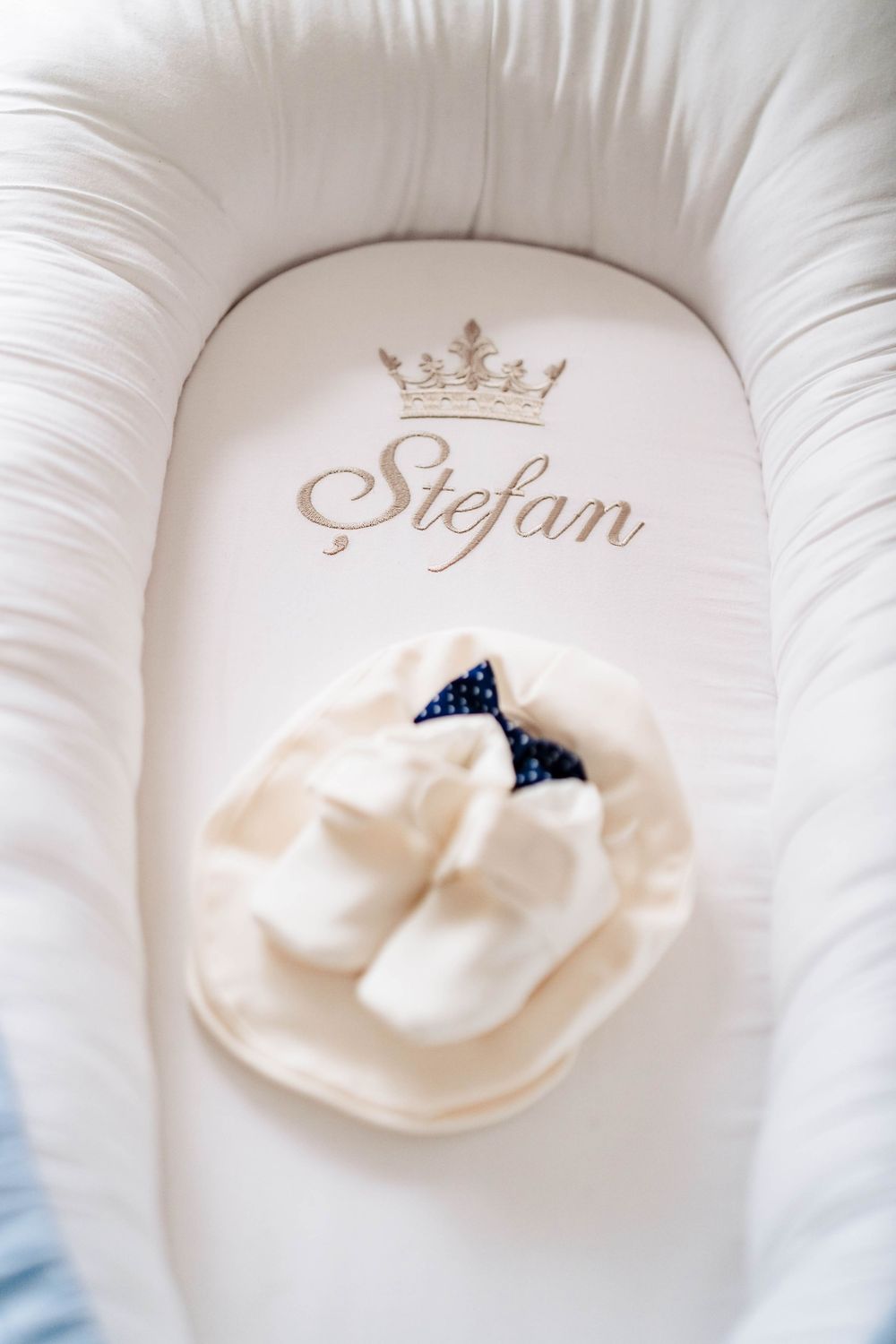 White cushion with embroidered crown and elegant design details.