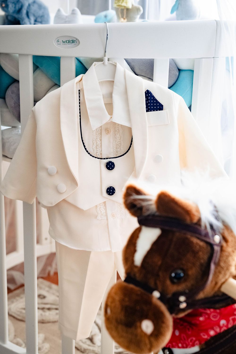 White miniature wedding outfits displayed on hangers with decorative plush toys.