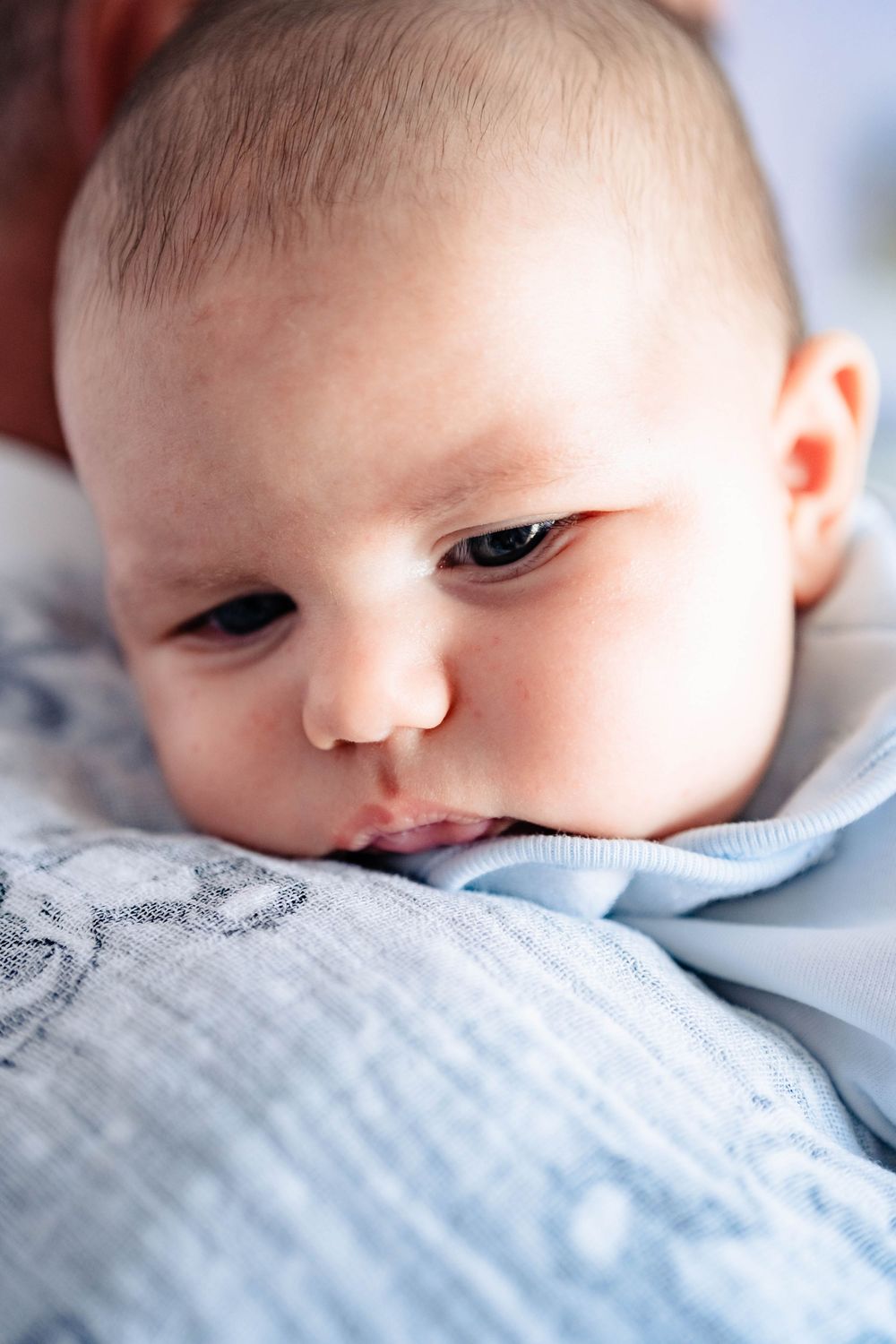 Close-up series of a baby's face resting on light blue textured bedding.