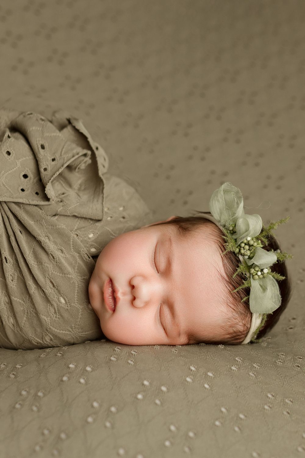 newborn baby girl asleep on back, wearing a dainty headband with green tulle bows in cedar park tx