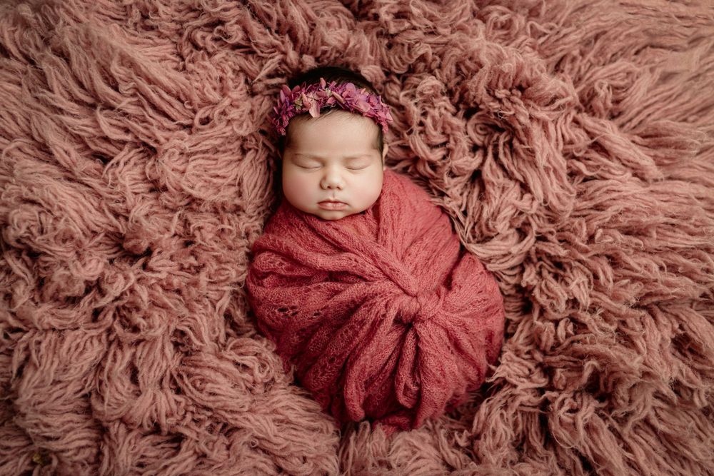newborn baby girl laying on back on a pink flokati, asleep for newborn photos in cedar park tx