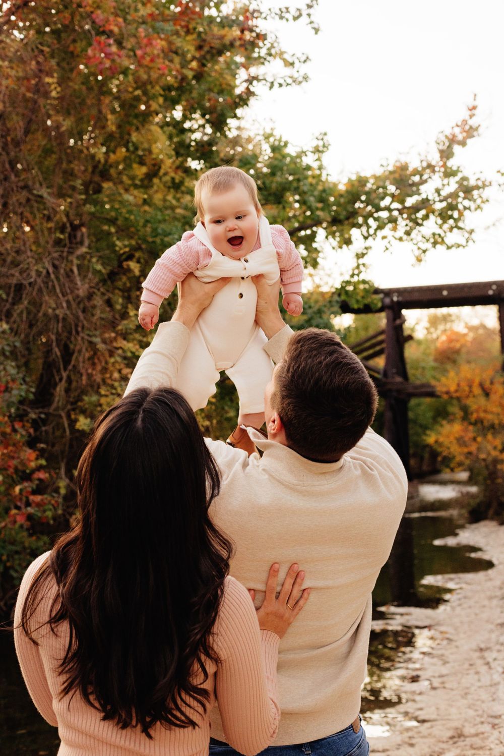 A family enjoying an autumn moment together by a river with fall foliage in the background.